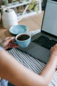 Stockfoto Frau am Laptop am Arbeiten mit Kaffeetasse in der Hand