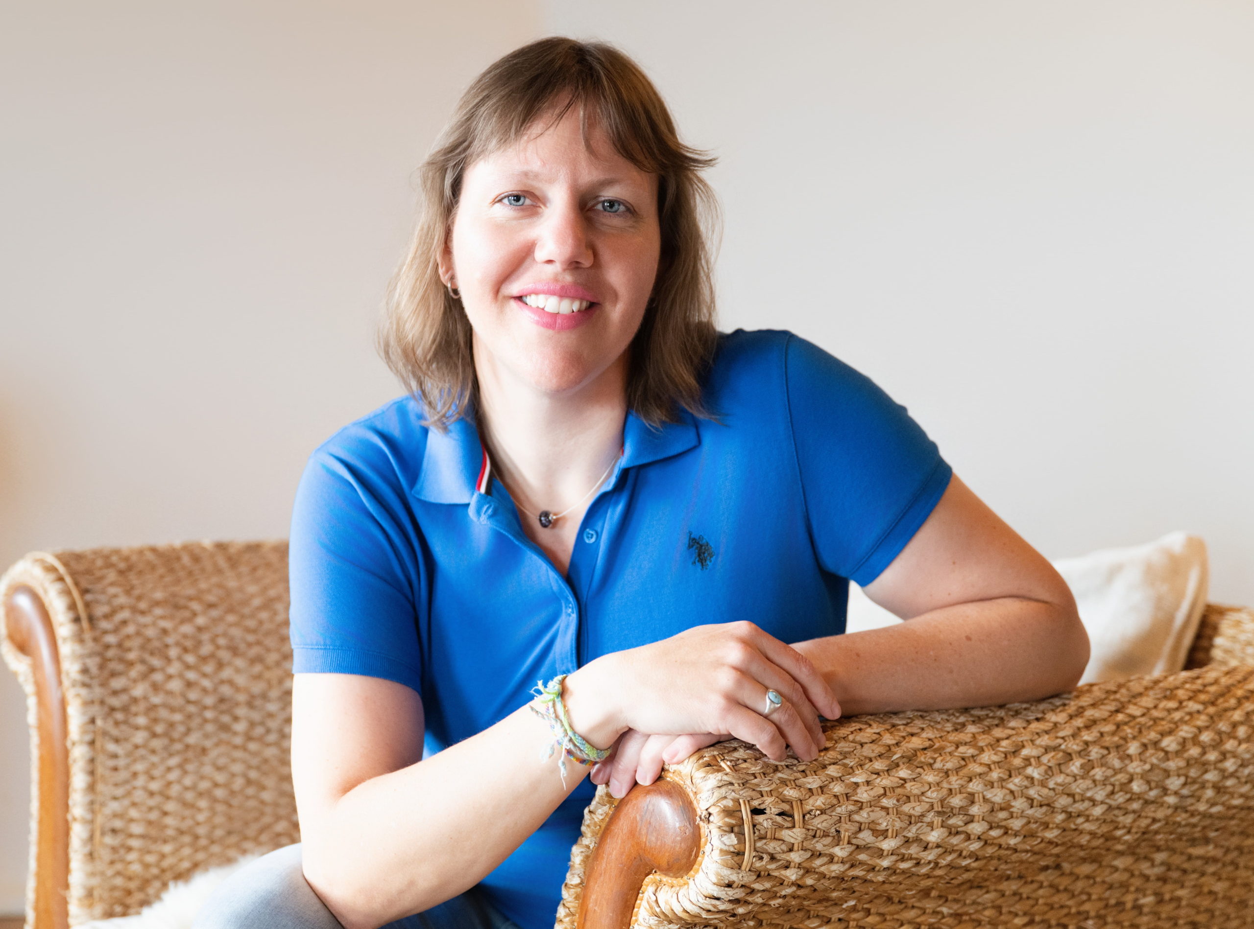 Tania Berchtold, CEO von Konfliktleichtigkeit sitzend auf einem Stuhl mit blauem Oberteil